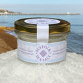 Suffolk Sea Salt jar with a gold lid, sitting on sea salt with the sea and Felixstowe pier in the background.